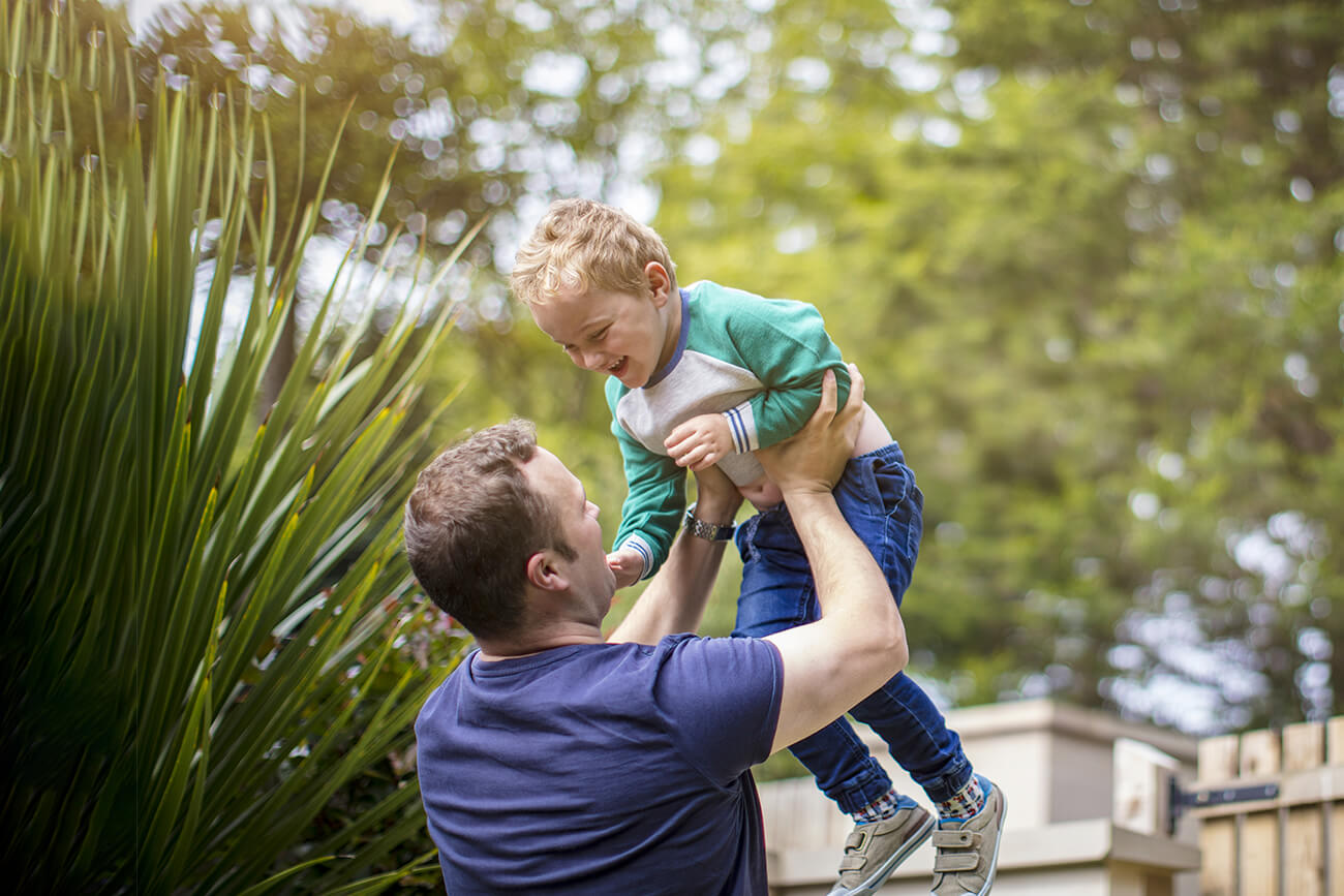 man holding up his son